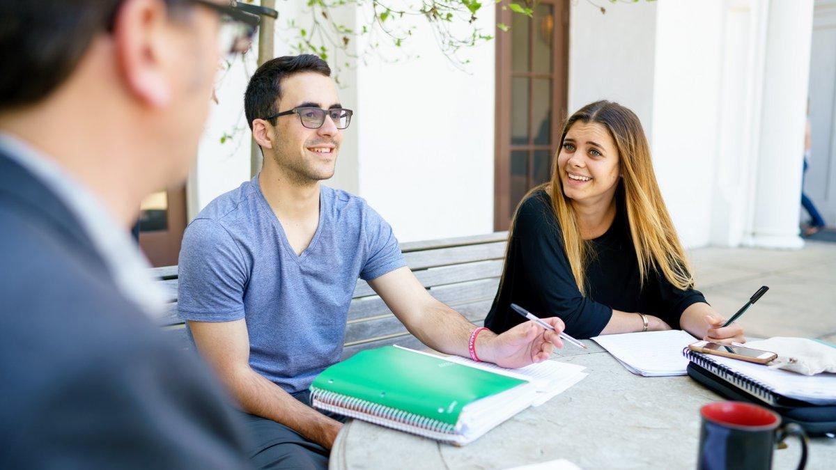 Students and a Writing Circle Facilitator laughing and discussing a paper outside the Writing Center.